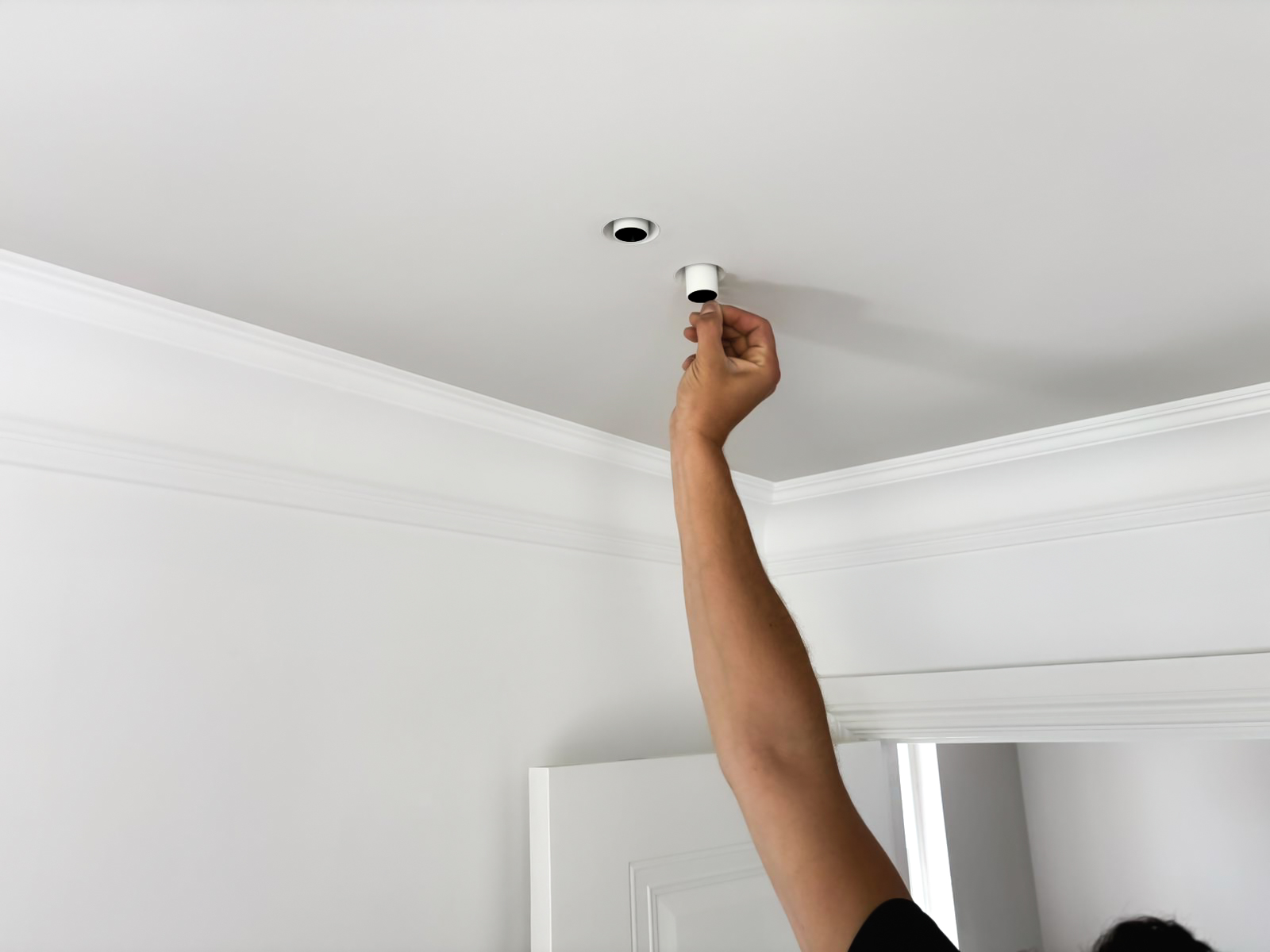 Electrician pulling out a full adjustable plaster-in spotlight from the ceiling