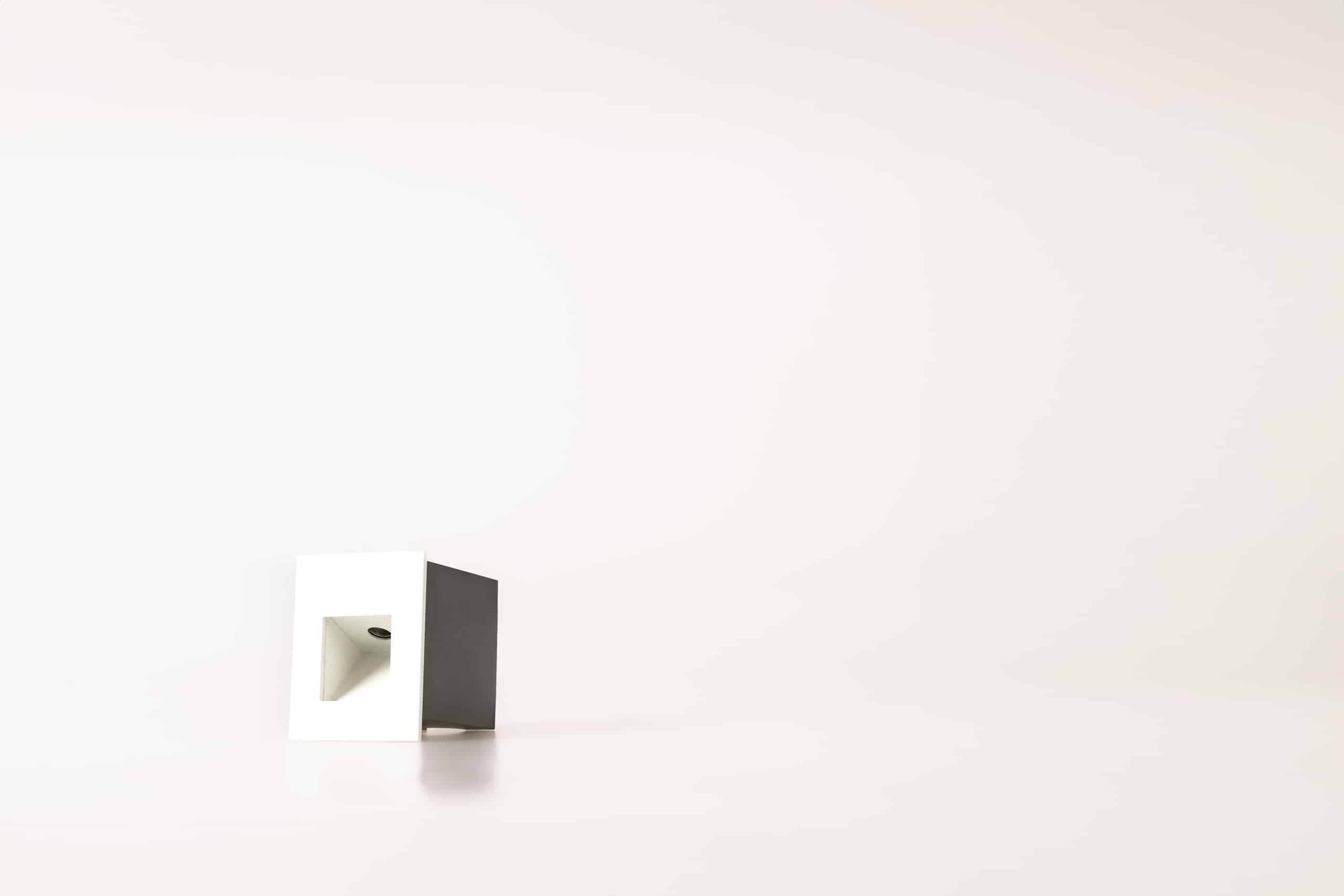 Matt white square low-level recessed step light for ground washing with a black installation sleeve