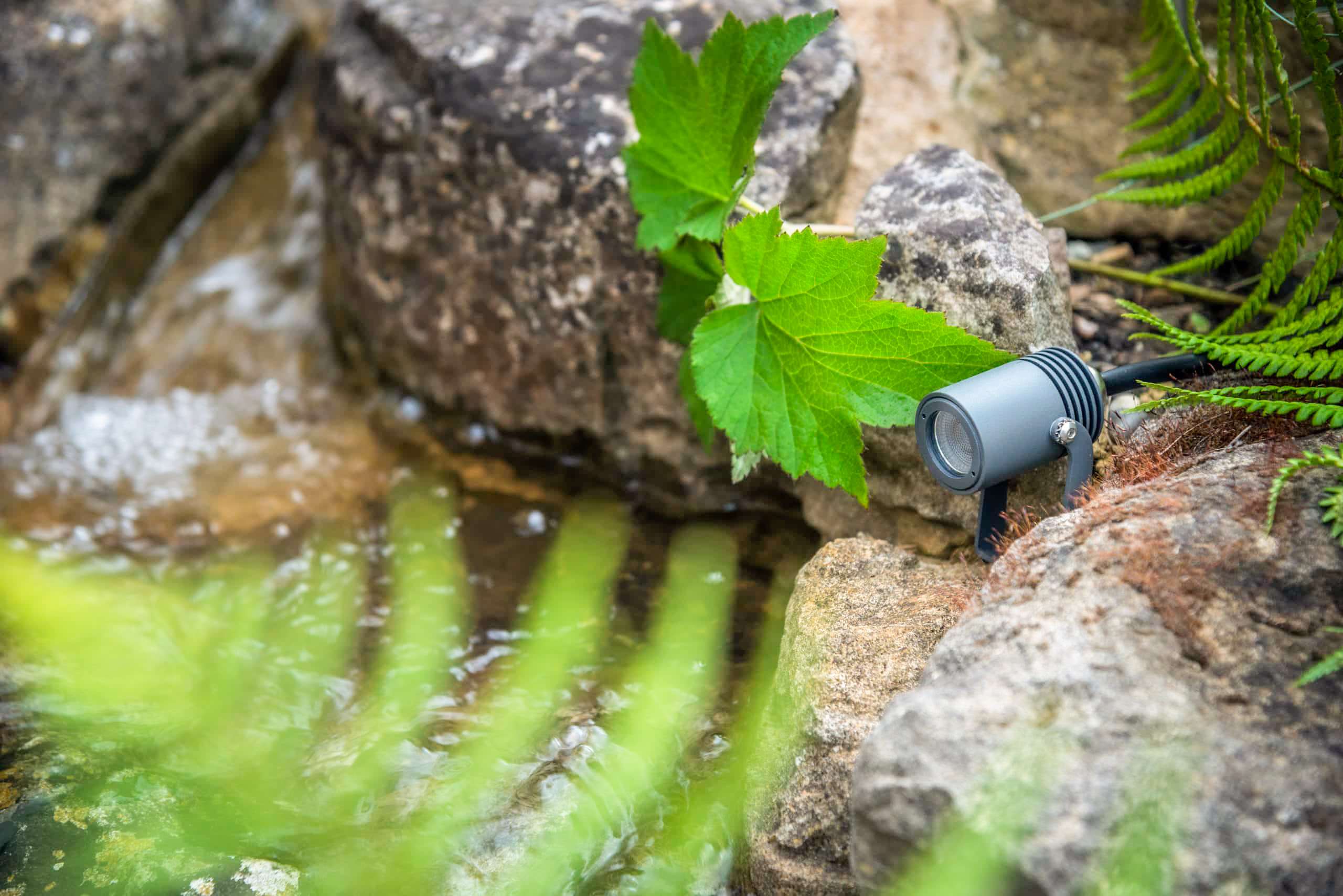 small exterior waterproof spotlight on rocks next to a stream